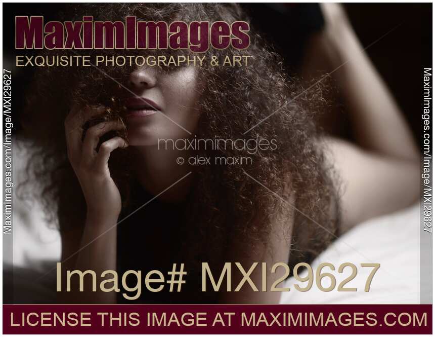 Sensual artistic portrait of a woman lying in bed with her hair covering her face