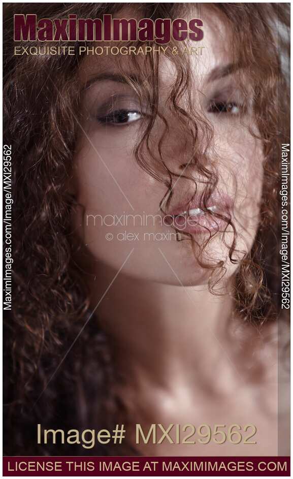Sensual beauty face portrait of a young woman looking through her curly hair