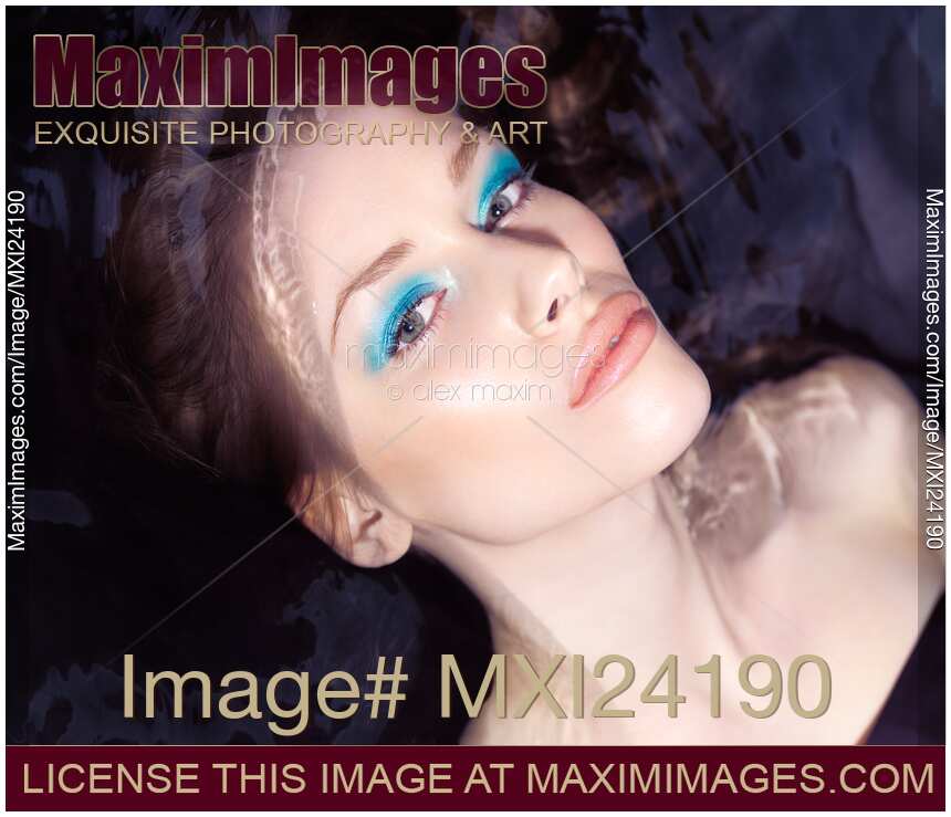 Sensual beauty portrait of a woman with blue makeup lying in water
