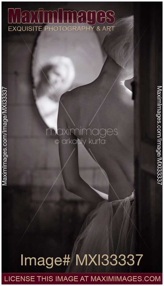 Sensual black and white portrait of a sexy woman standing by the mirror, rear view of her back