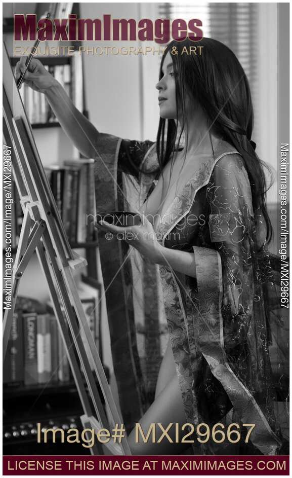 Sensual black and white portrat of woman artist painting half nude in her home studio on easel