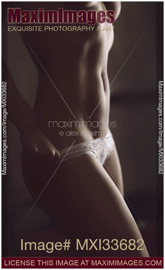 Sensual boudoir closeup of a sexy topless half-nude woman undressing taking off her underwear
