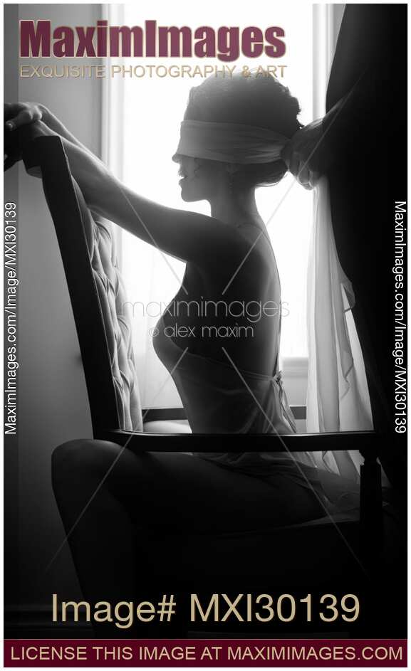 Sensual couple black and white portrait Man tying blindfold on a beautiful sexy woman sitting in a chair