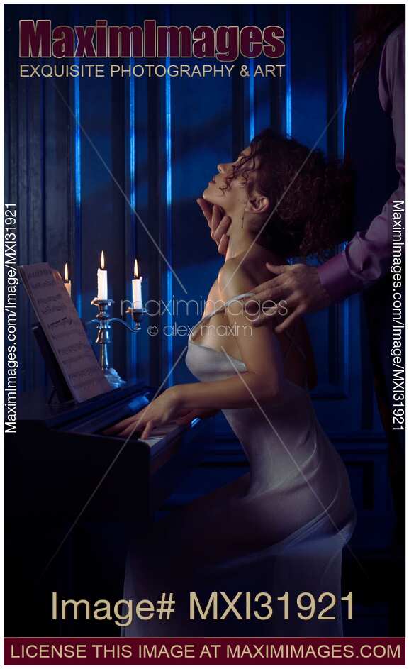 Sensual couple romantic portrait man caressing neck of a woman playing the piano in candle light