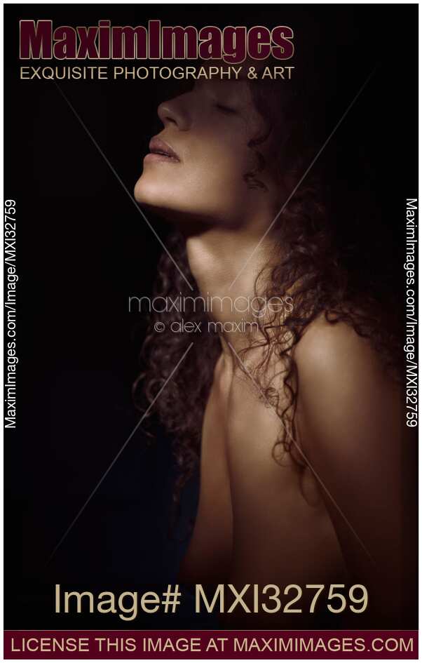 Sensual dramatic closeup of woman face and neck and bare chest in shadows