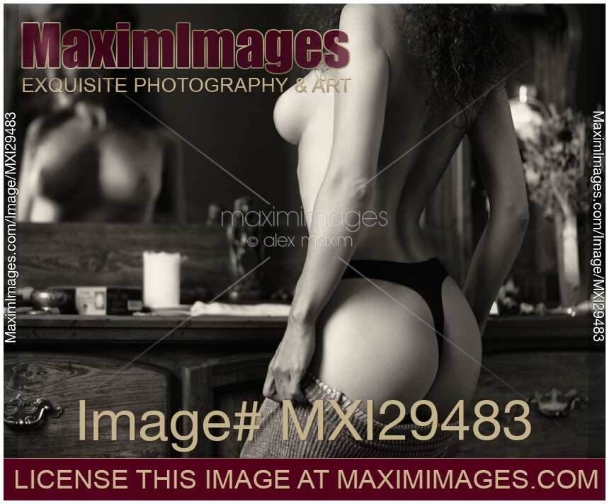 Sensual erotic black and white portrait of a sexy topless woman in underwear dressing up