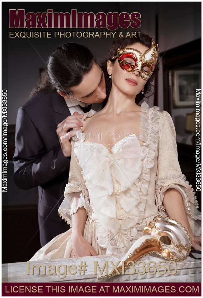 Sensual portrait of a couple, man kissing beautiful woman in carnival mask and vintage Venetian dress. Casanova seduction concept.