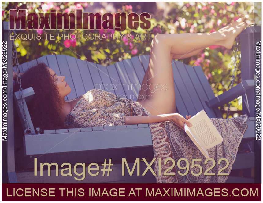 Sensual portrait of a sexy young woman sleeping in garden with book in hand