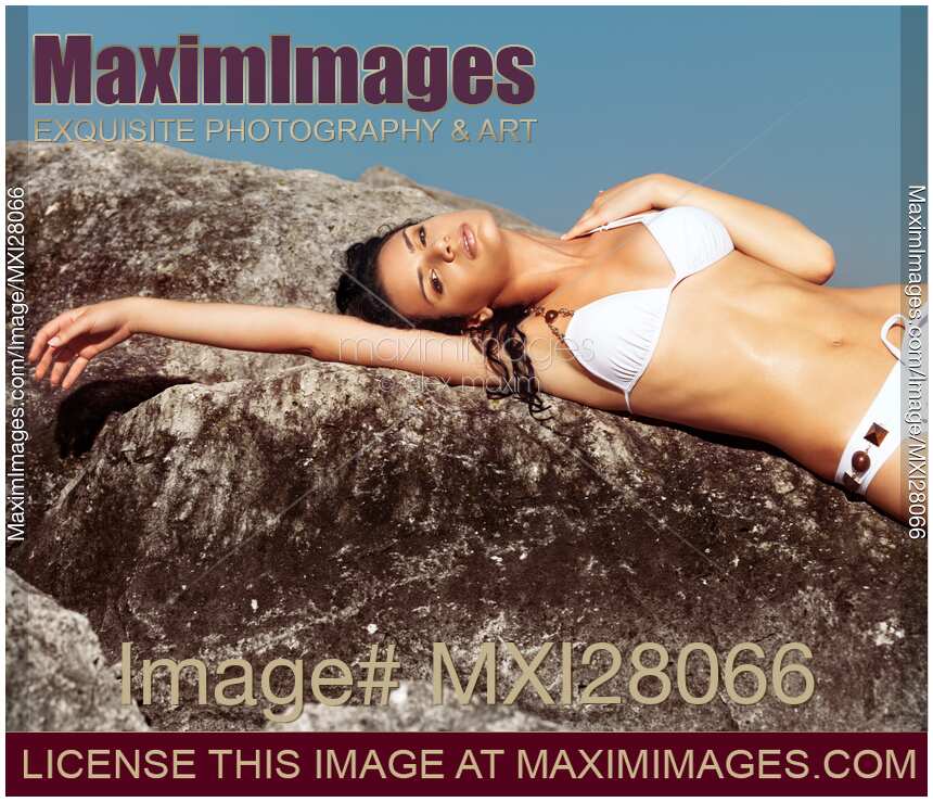 Sensual portrait of a woman in bikini on a rocky shore