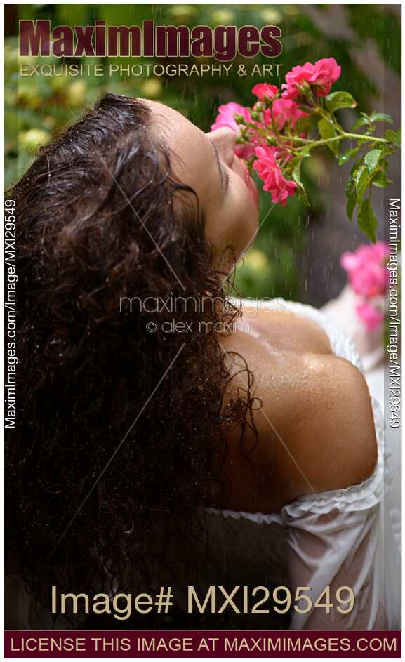 Sensual portrait of a woman smelling roses in a garden in the rain