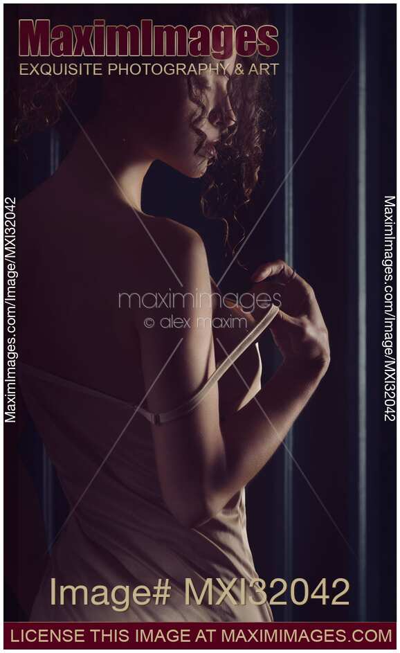 Sensual portrait of a woman taking off a shoulder strap of her camisole night gown