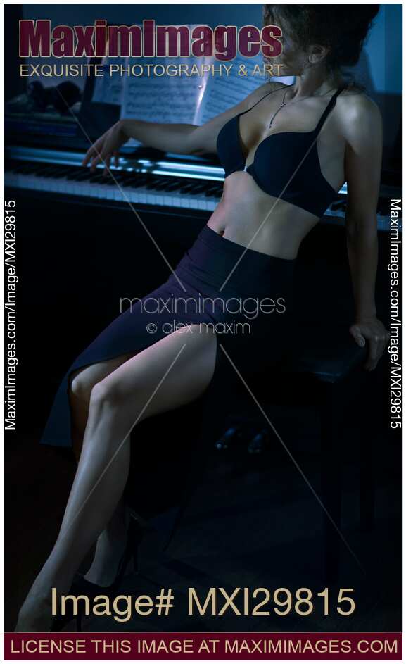 Sensual portrait of beautiful sexy woman leaning back against piano keyboard