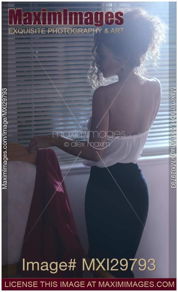 Sensual portrait of sexy woman standing half undressed by the window at night