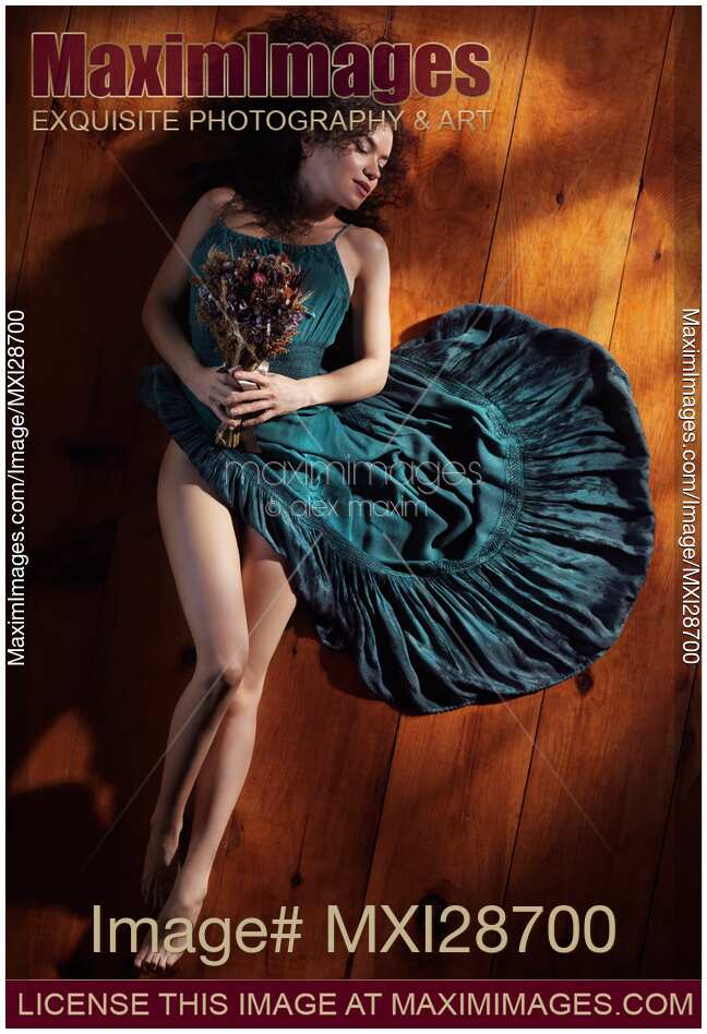 Sensual portrait of woman in green dress with bare legs lying on the floor