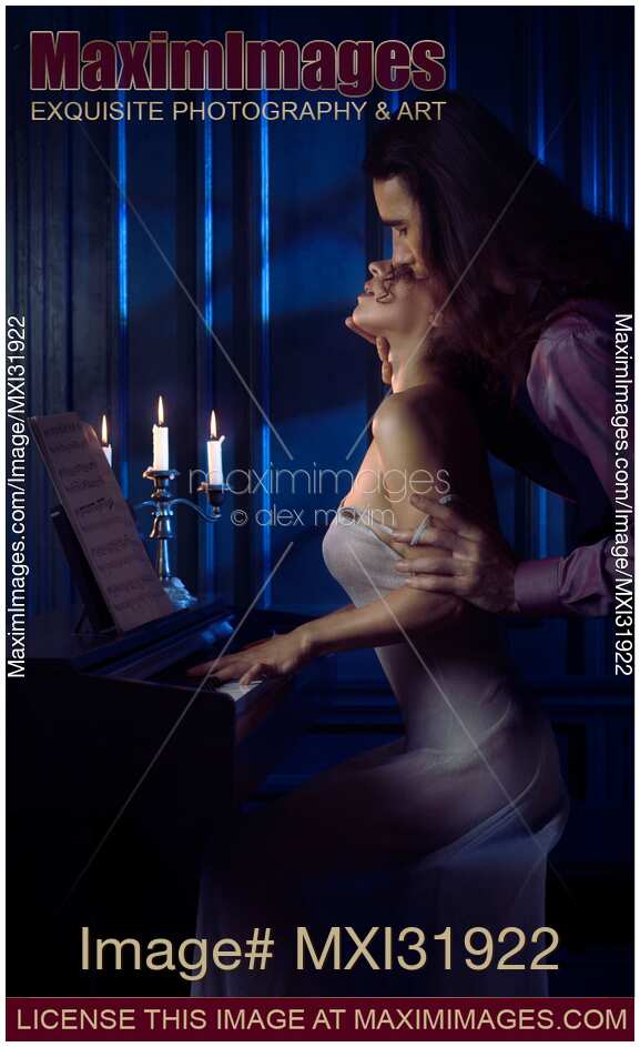 Sensual romantic couple man with long hair caressing woman at a piano reaching to kiss
