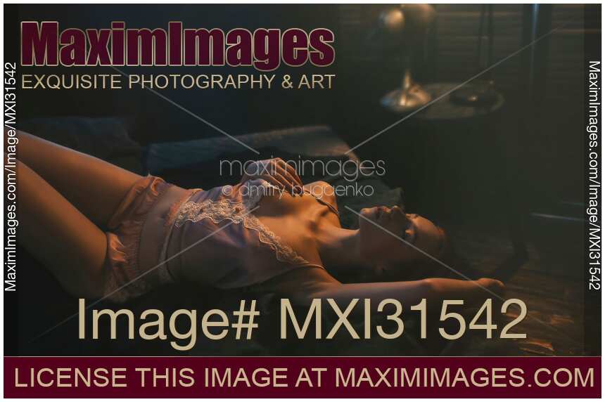Sensual romantic photo of a woman in lingerie on a bed in dim light gently caressing herself
