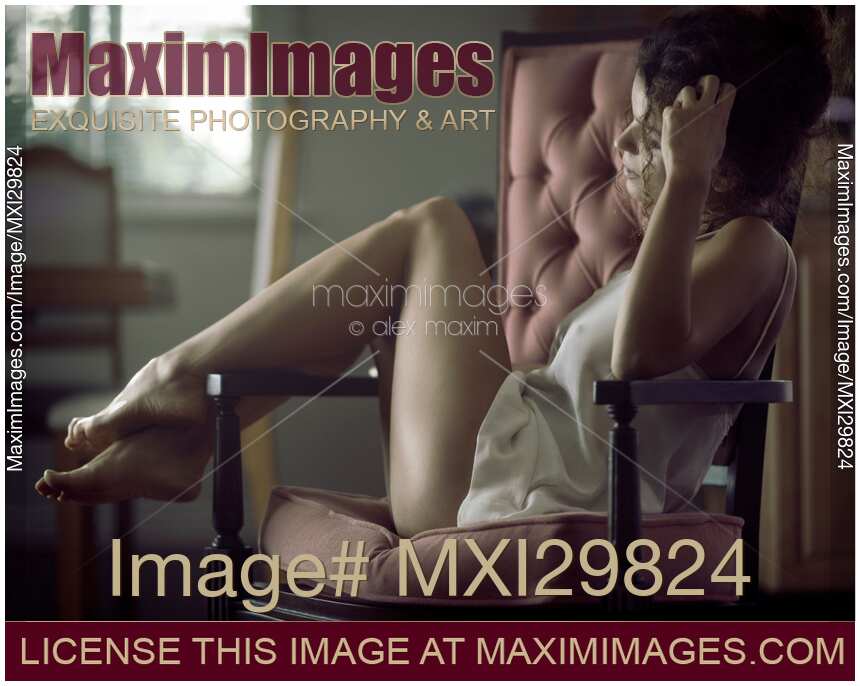 Sensual romantic portrait of young woman in night shirt sitting in armchair
