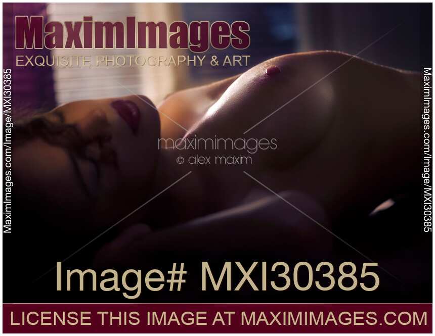 Sensual romatic portrait of a woman lying down naked closeup of her cheast in dim light implying making love