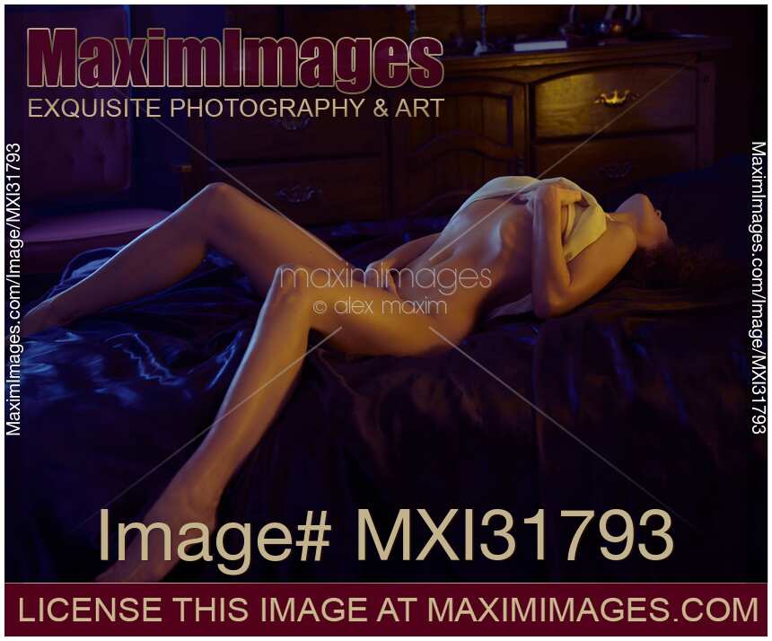 Sensual woman caressing herself lying half-naked with her body arching upwards on a bed
