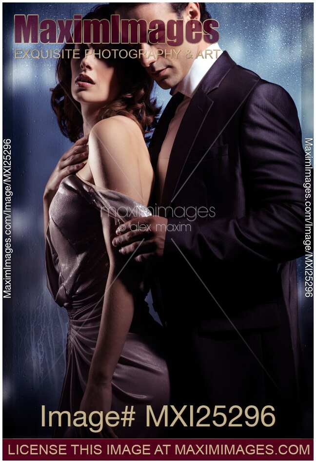Sensual young couple in front of a window romantic portrait of a man slowly undressing a woman