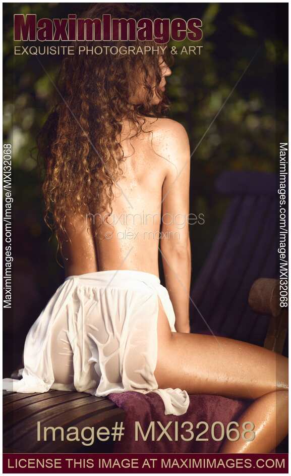 Sexy beautiful woman with long hair and wet skin sitting topless in wet sheer beach skirt Rear view erotic portrait