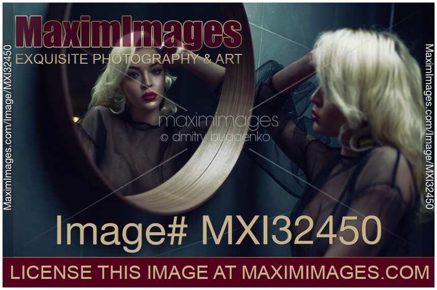 Sexy blond woman looking into a round mirror