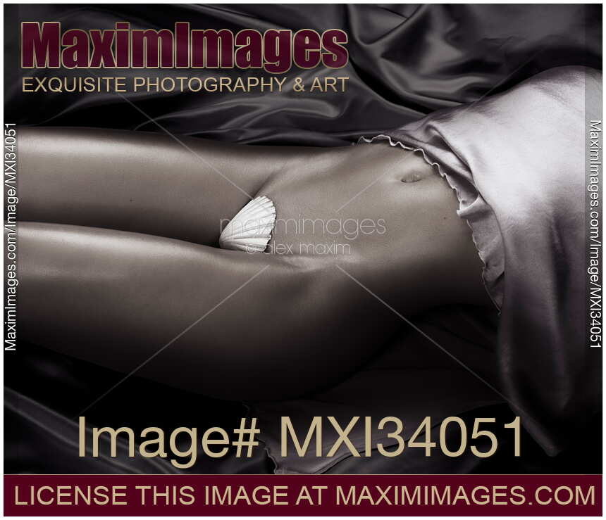 Sexy closeup of half-naked woman midsection with sensual curves lying on black satin with pearly white seashell covering her nude body