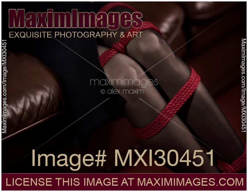 Sexy closeup of woman knees in stockings with her legs tied up with a red bondage rope