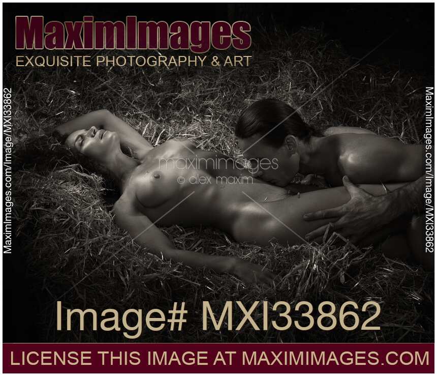 Sexy couple man and woman making love lying naked on straw in dark shadowy barn. Sensual romantic black and white nude scene.