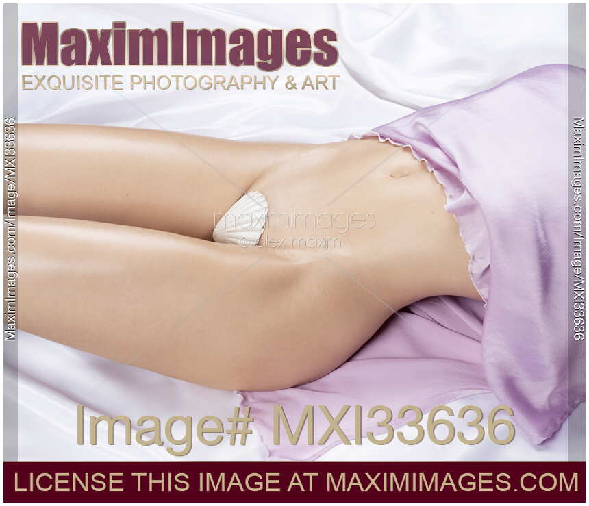 Sexy half-naked woman body midsection with sensual curves lying on white satin bed a pearly seashell covering her nudity