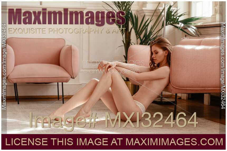 Sexy half naked young woman sitting on the floor of a brightly lit room