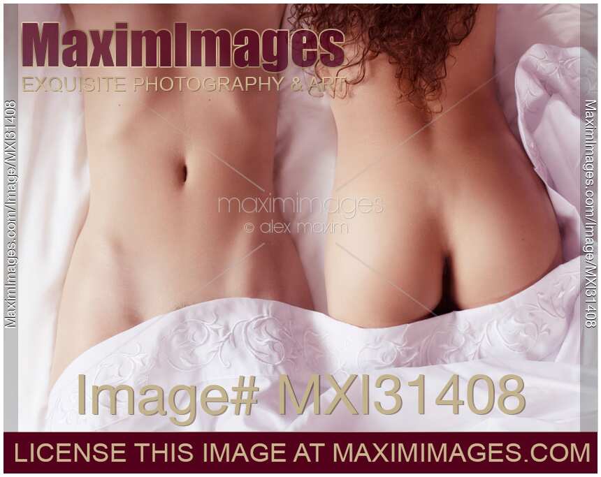 Sexy lesbian couple two women lying together on bed sheets sensual close-up of half nude bodies