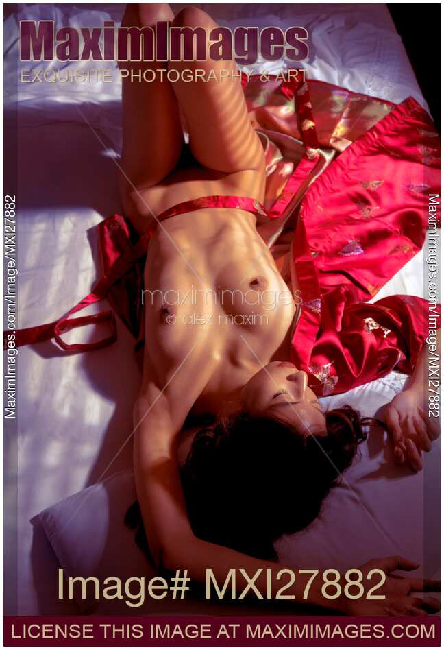 Sexy nude asian woman lying in bed on red kimono