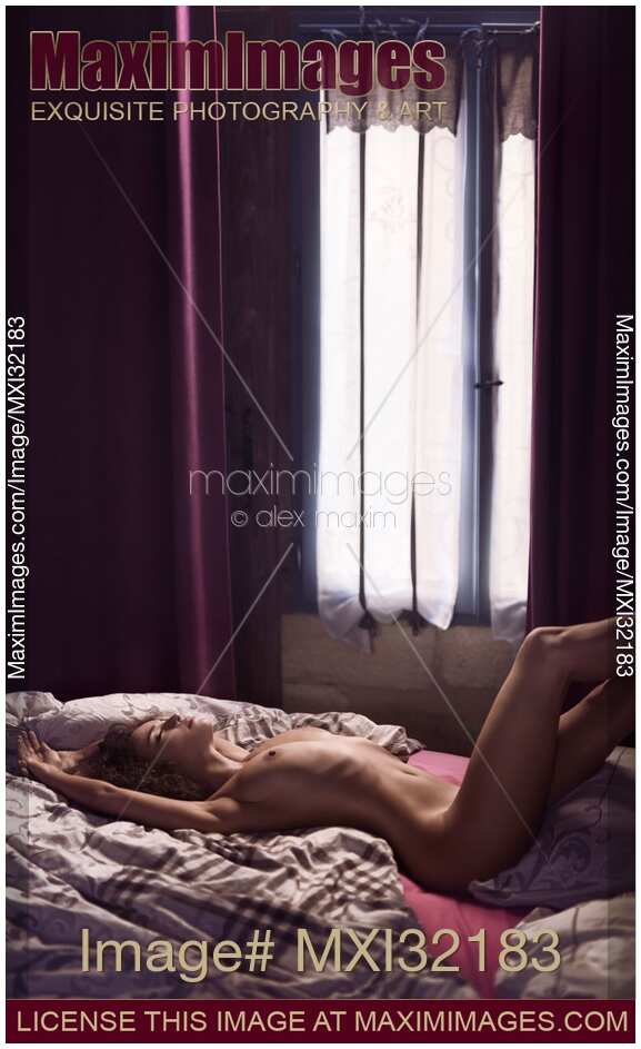 Sexy nude beautiful woman lying relaxed on a bed by a window