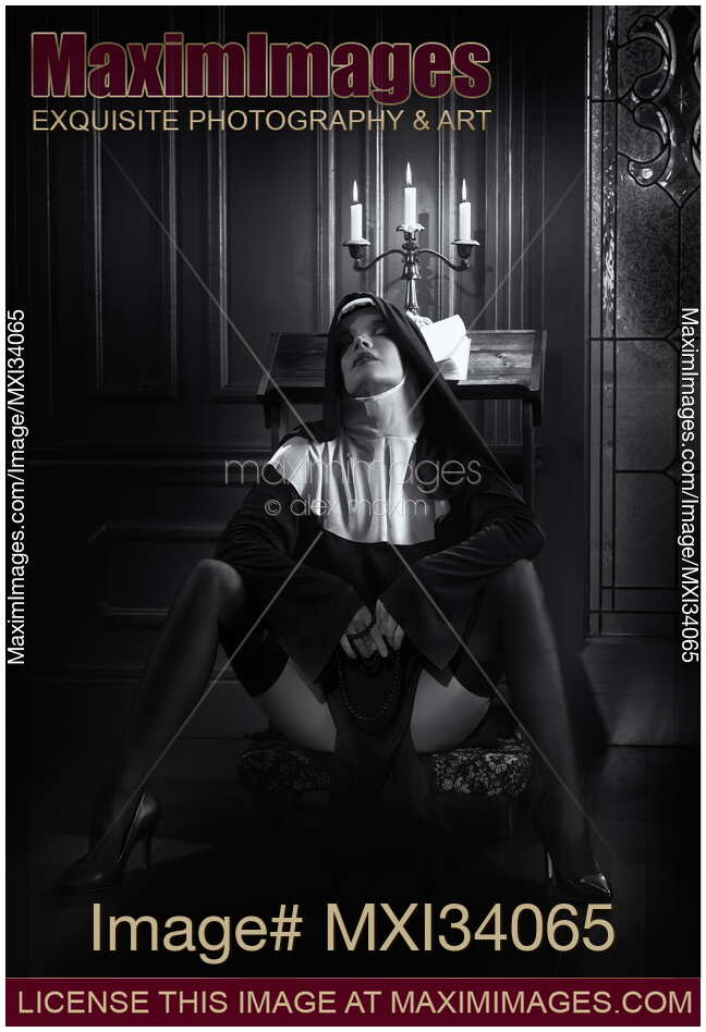 Sexy nun sitting in provocative pose on praying bench with her legs in stockings spread wide apart Black and white