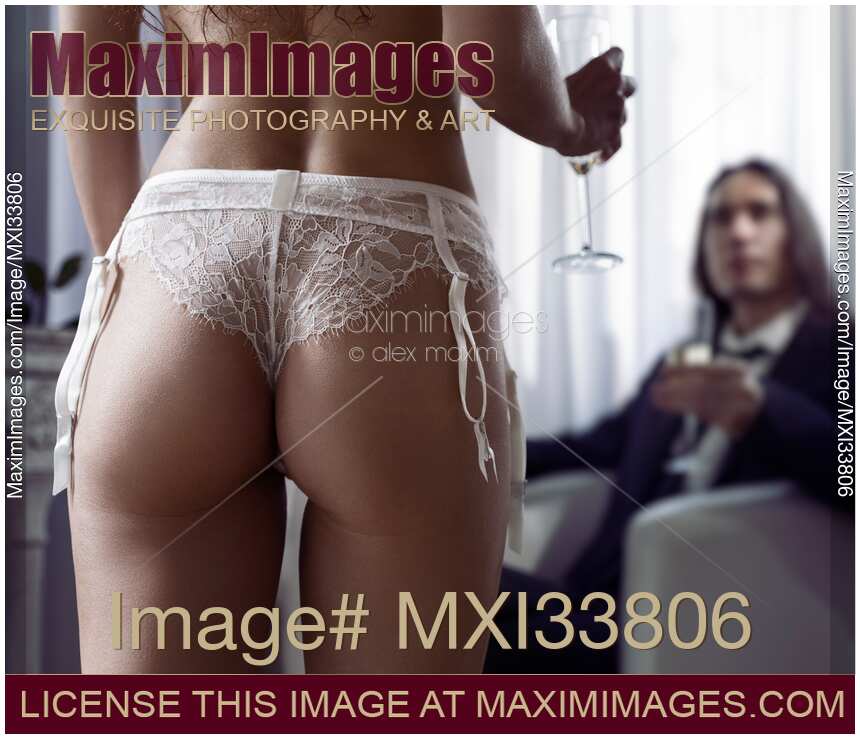 Sexy woman approaching a man with glass of wine. Artistic closeup of woman buttocks in sexy white lingerie.