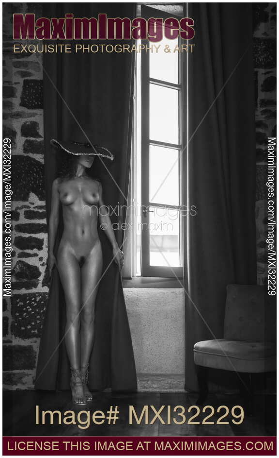 Sexy woman in a hat standing naked by a window curtain Black and white Fine art nude