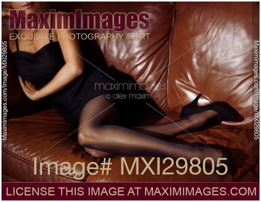 Sexy woman lying on brown leather couch in black dress stockings and high heels