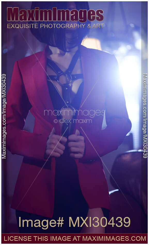 Sexy woman with short black hair wearing bondage leather harness and underwear under a red suit jacket