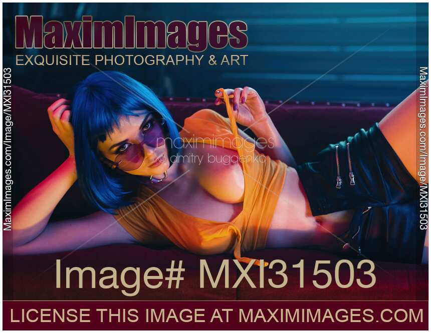 Sexy woman with short blue hair taking off her top revealing her sensual breasts