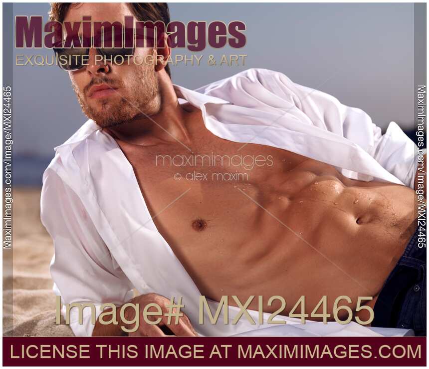 Sexy young man lying on sand at the beach