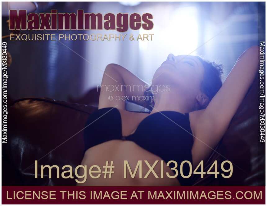Sexy young woman in underwear leaning back on a sofa