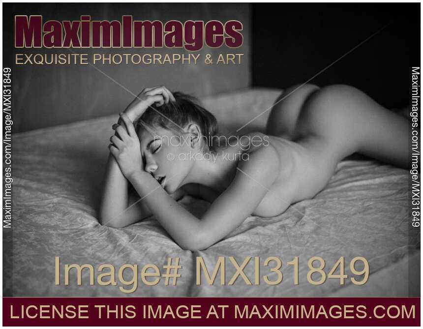 Sexy young woman lying naked on bed with an ecstatic expression black and white