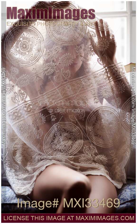 Sexy young woman undressing looking through sheer white lace nightgown covering her face and naked body