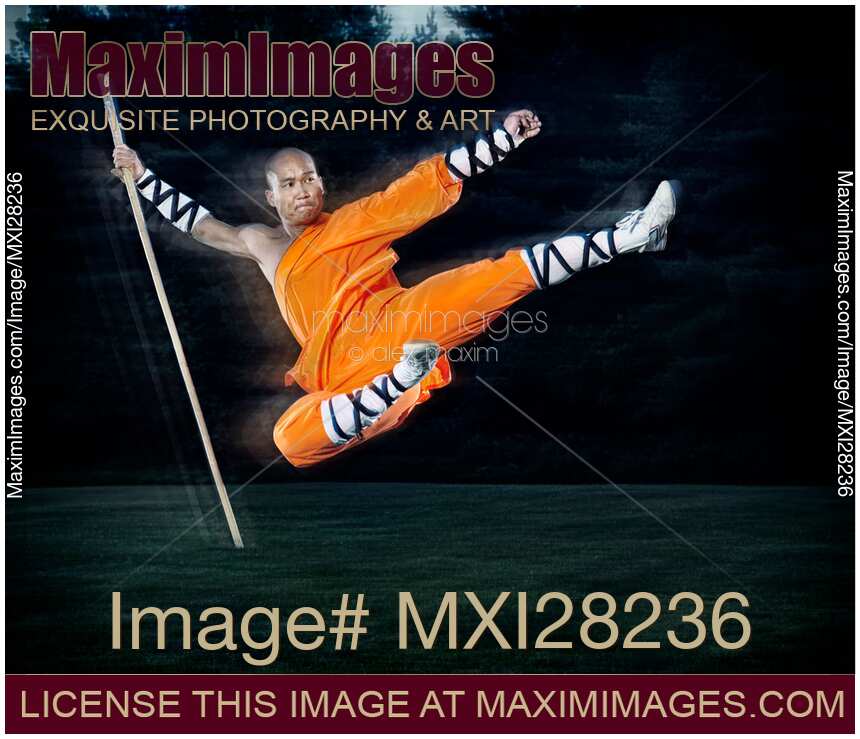 Shaolin warrior monk performing flying kick with a staff
