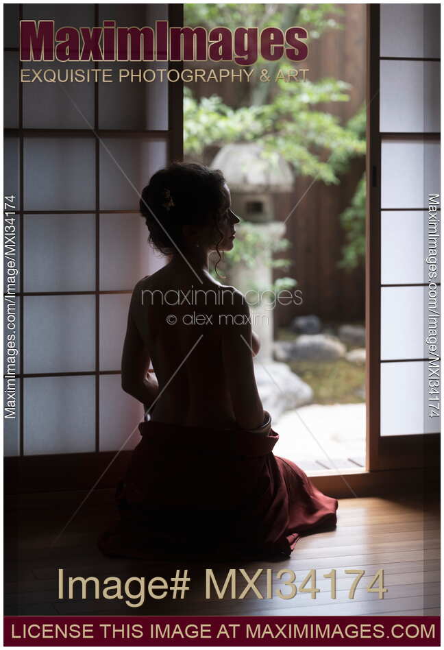 Silhouette of a beautiful woman with naked back sitting by an open door of a Japanese house with Zen garden