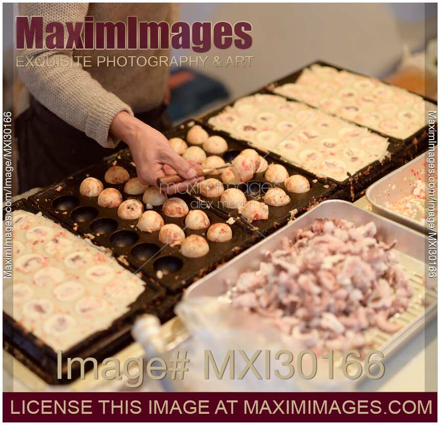 Street food vendor making Takoyaki grilled octopus balls at a street food market in Japan