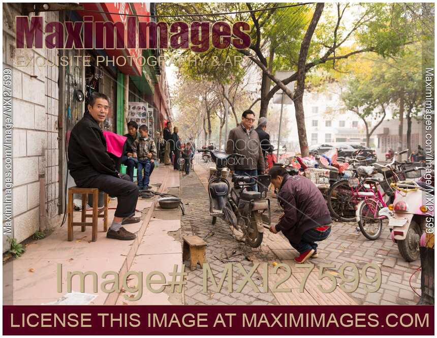 Street scenery of person repairing scooter in China