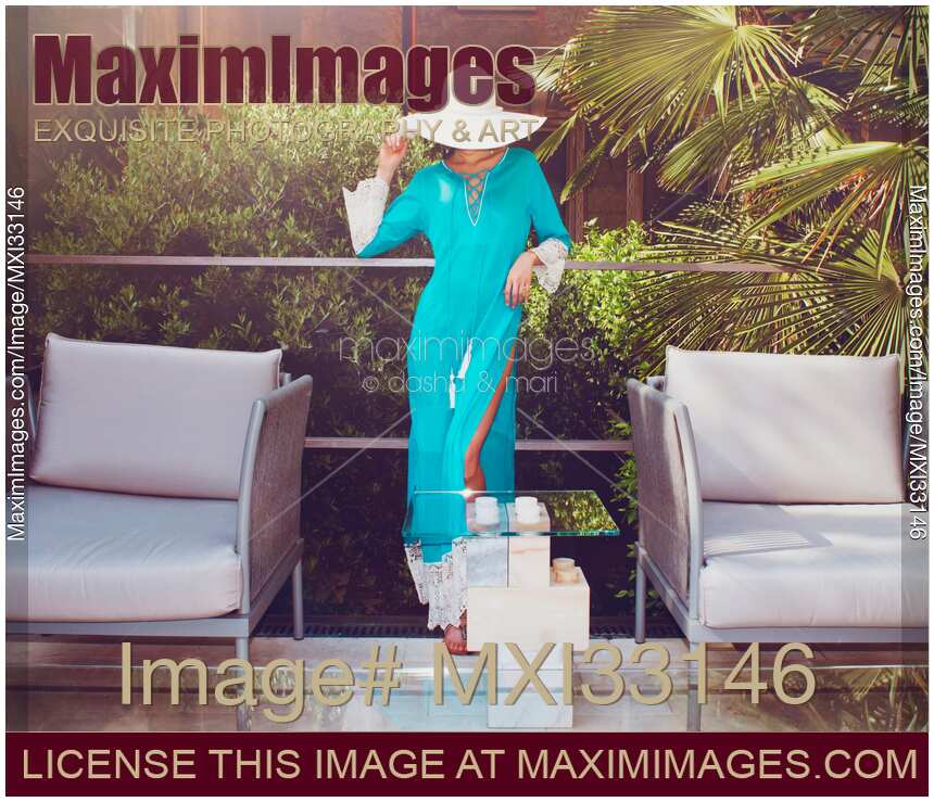 Summer beach fashion glamorous portrait of a beautiful woman wearing a turquoise beach caftan dress and a hat