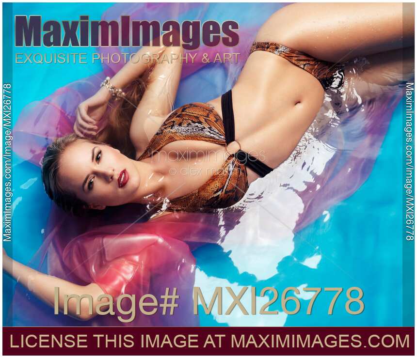 Swimsuit glamour portrait of a beautiful woman in bikini lying in colorful blue with red water